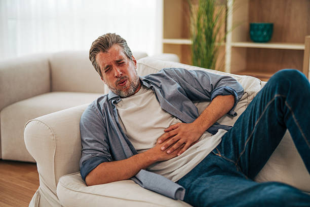 istock Mature man suffering from stomach ache lying on sofa at home 2228754699