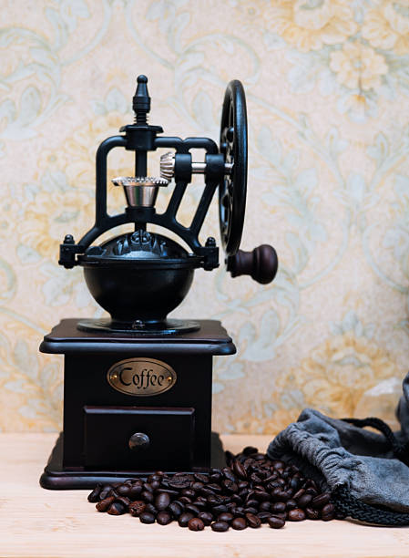 Raw coffee beans photographed with a hand grinder laying on a wooden table top.