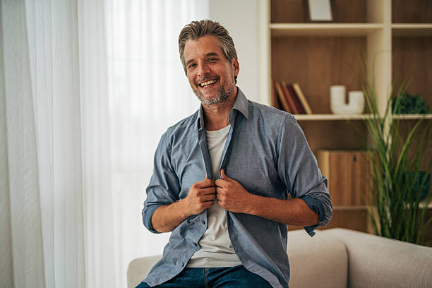 istock Smiling mature man buttoning his shirt at home 2228756943