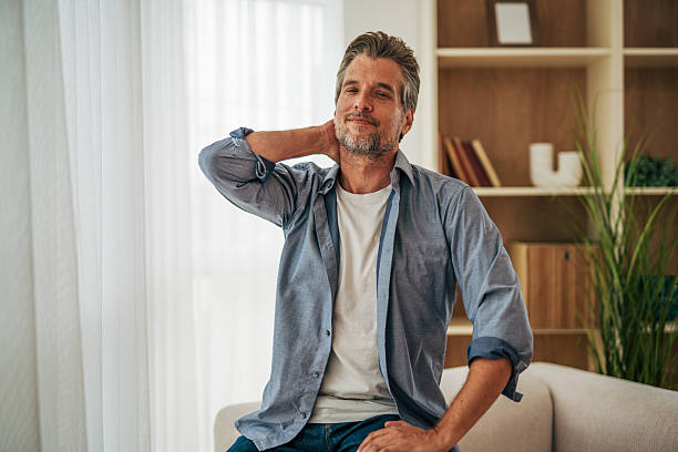 istock Relaxed mature man sitting on sofa at home touching neck 2228757187