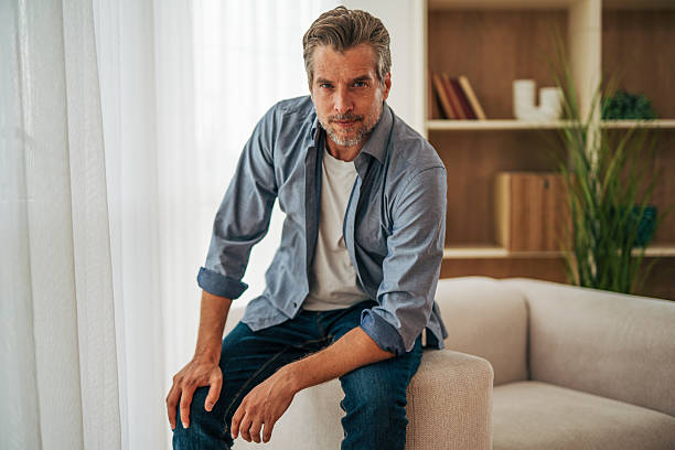 istock Confident mature man sitting on sofa armrest at home 2228757230