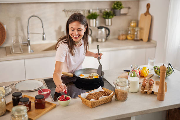 istock Young woman cooking fried eggs for breakfast in a modern kitchen 2228758961
