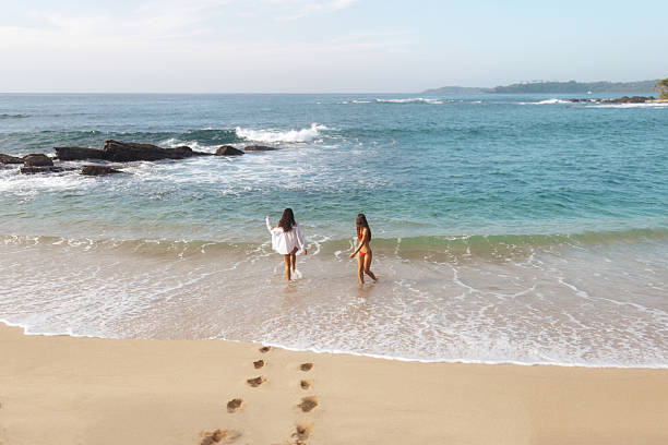 istock Women in Bikinis Strolling into the Ocean on a Calm Tropical Beach 2228761347