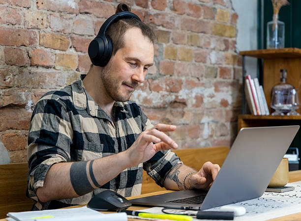 istock Man Engaged in Work at Home Using Laptop and Wearing Headphones 2228763000