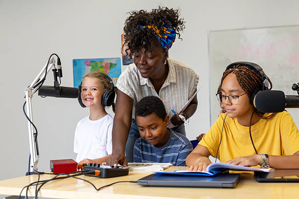 istock Teacher helping students recording podcast in school radio studio 2228763145