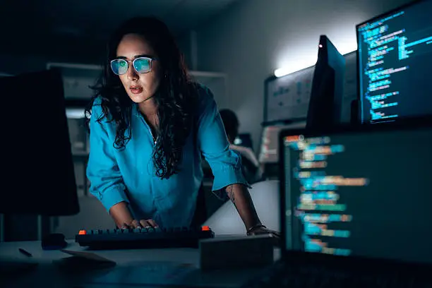 Photo of Hispanic Female software developer coding at night in office