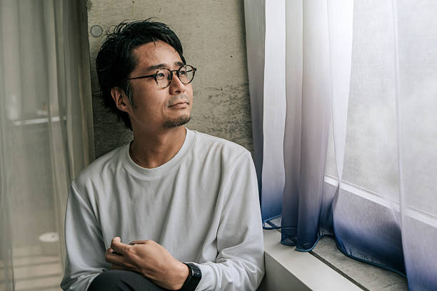 Pensive Japanese Man Sitting by Window in Thoughtful Mood