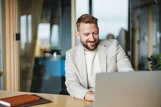 istock Smiling Businessman in Office Using Laptop 2228766632