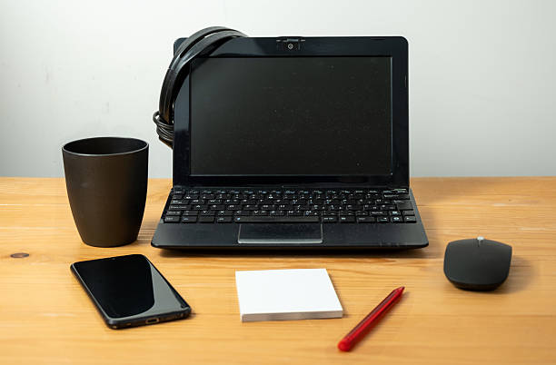 Laptop computer with notebook, pen, smart phone, mug and headphones on the office desk.