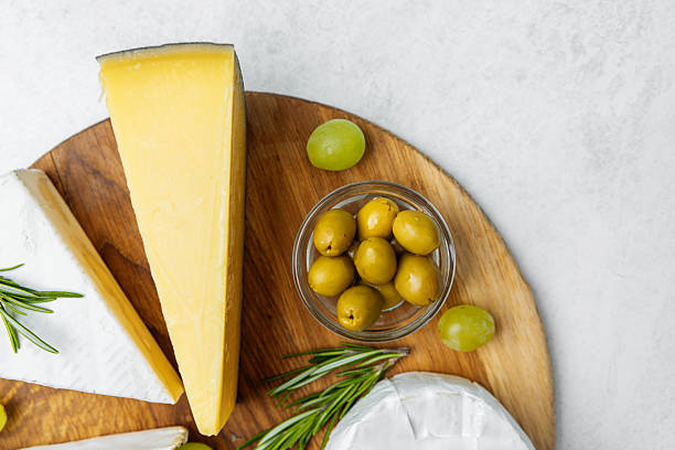 istock Cheese platter with olives and herbs arranged on a wooden board 2228770416