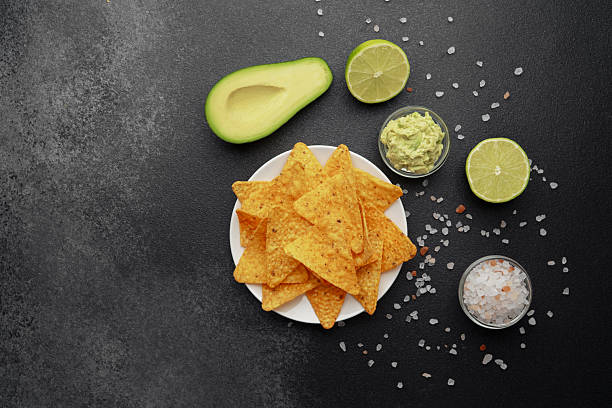 istock Nacho chips with avocado, lime, salt and guacamole on black background 2228770458
