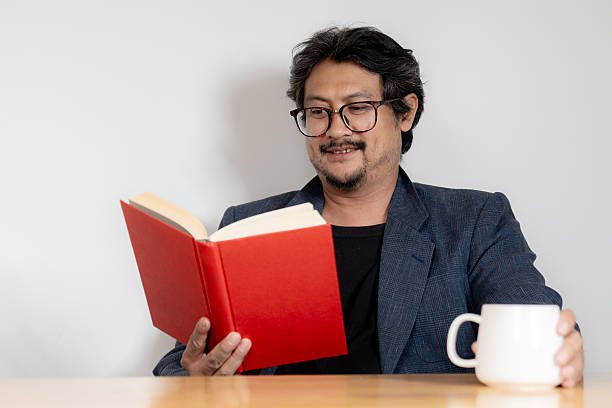 Young man with glasses reading book at home