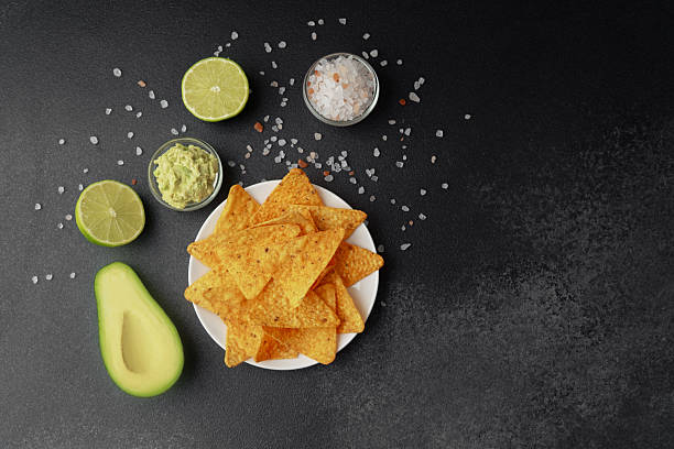 istock Nacho chips with avocado, lime, salt and guacamole on black background 2228781286
