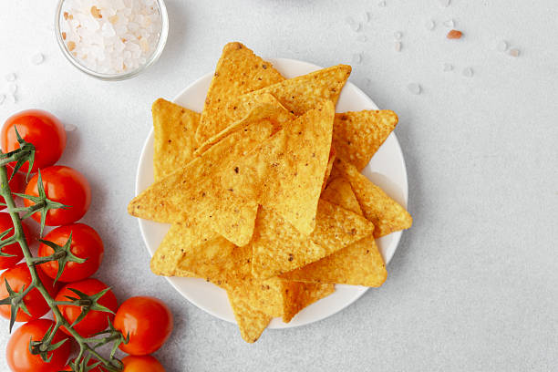 Crispy nachos with tomatoes, salsa and salt on white background