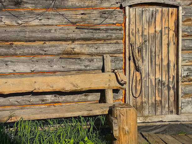 istock A charming rustic cabin with a wooden door and handcrafted bench in sunlight. 2228783059
