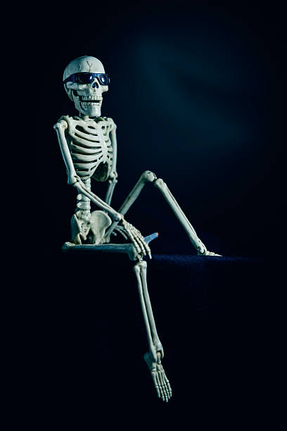 istock Silly Halloween Skeleton in Sunglasses Sitting Down in Dart With Cigarette 2228783728