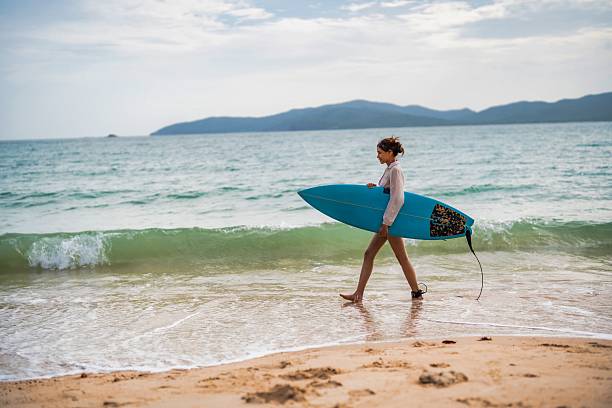 istock Surfer walks along the shore with a blue surfboard during early evening at the beach 2228783887