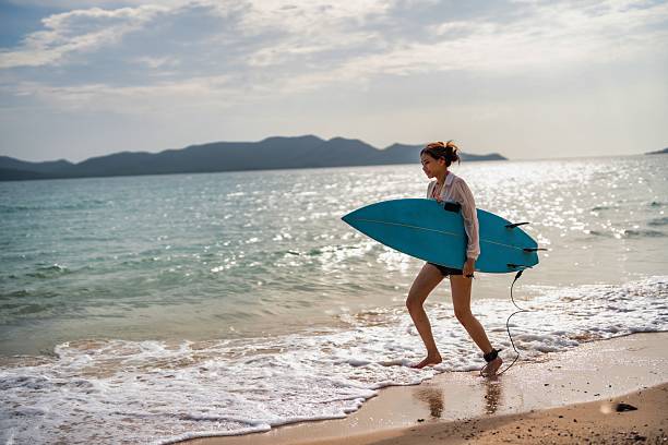istock Surfer walks along the beach with a blue surfboard during a sunny evening 2228783907