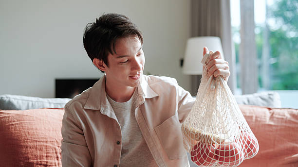 Asian man holding fruit in reusable bag