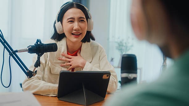 istock Generation Z podcasters collaborating wearing headphones discussing topics during recording session together in home studio. 2228791320