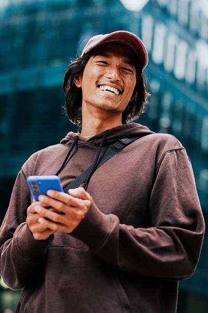 istock Smiling Young Asian Man Using Smartphone Outdoors in Urban Cityscape 2228793546