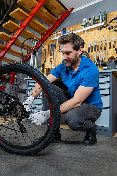 istock Bearded man servicing bike wheel in indoor workshop surrounded by tools drawers and industrial staircase during bicycle maintenance 2228794361