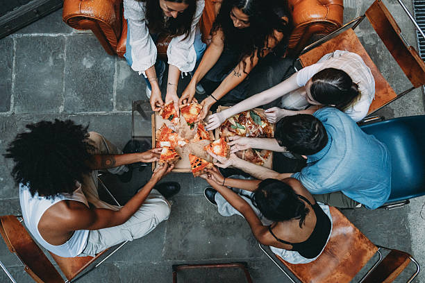 Group of friends grabbing slices of pizza from above