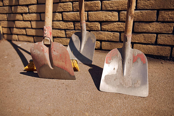 Several dirty old shovels leaned to a brick wall.