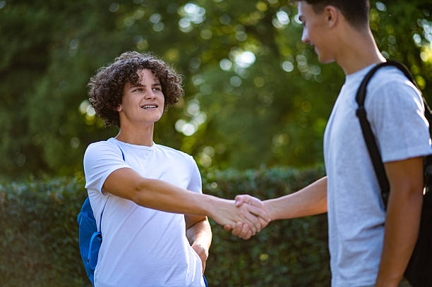 istock Two friends meeting, shaking hands and looking pleased 2228801617