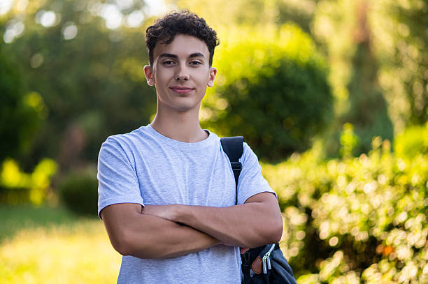 istock Dark-haired teen looking confident and smiling while standing in the park 2228801726