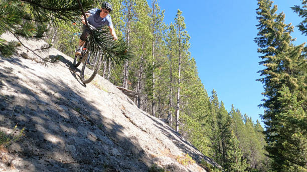 istock Young man descends steep rock slab on mountain bike 2228802480