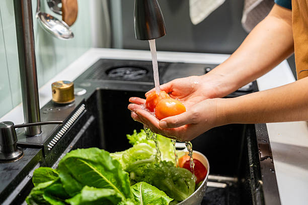 istock Hands gently rinse fresh salad greens under flowing water in a home kitchen. In a kitchen sink vibrant salad vegetables are thoroughly washed clean eating. 2228803410
