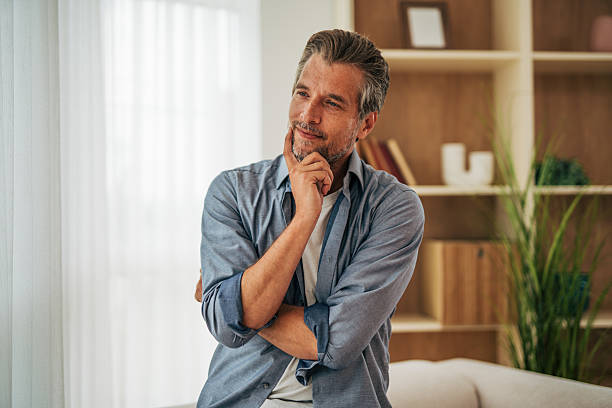istock Mid adult man thinking and smiling at home 2228803485