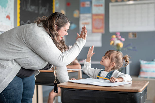 istock Teacher and Student High-Fiving in Classroom During a Learning Activity 2228803493
