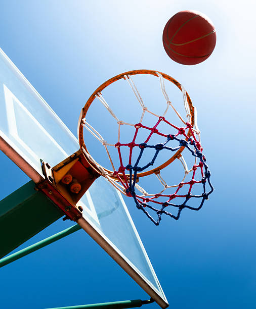 istock Basketball ball and hoop with net outdoors against blue sky 2228805407