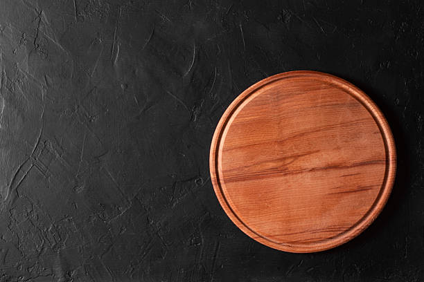 istock Round wooden cutting board on black background. 2228806480