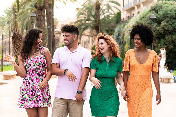 istock Four happy friends walking and talking together on vacation 2228810395