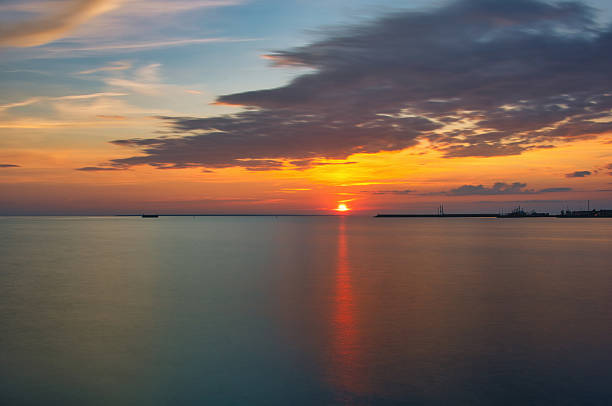 istock Dramatic Sunset Over Calm Sea with Silhouetted Harbor - Peaceful Evening Sky 2228812489