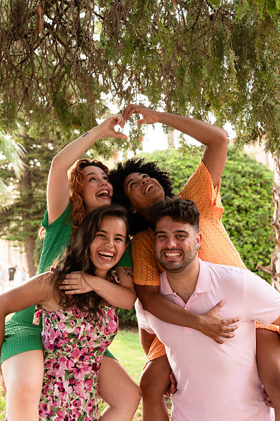istock Four happy friends piggybacking and making heart shape with hands 2228812911