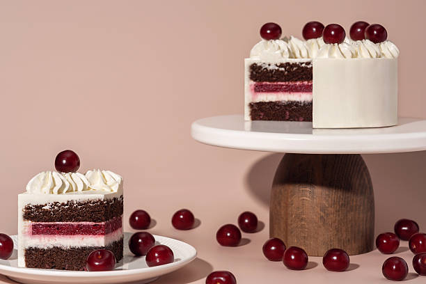 Bento cake with layers of chocolate, cherry filling, and whipped cream, beautifully presented on a wooden stand, surrounded by fresh cherries, showcasing a delightful dessert experience
