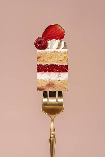 istock Vanilla sponge bento cake layered with raspberry and strawberry, topped with whipped cream and fresh fruit, presented on a golden fork against a soft pastel background, dessert concept 2228813904