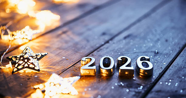 istock Shiny 2026 Numbers Surrounded by Glowing Star Lights on Wooden Surface 2228814118