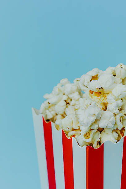 Red and white striped popcorn container on a blue background