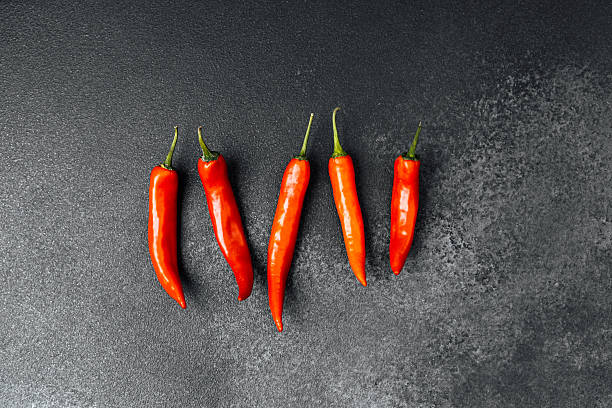 istock Red chili peppers arranged neatly on a dark background in a kitchen setting 2228816811