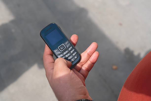 A bearded man using an old-fashioned mobile phone while enjoying a digital detox. He appears calm and focused, intentionally disconnecting from modern technology. Concept of minimalist lifestyle, mental health, and tech-free moments.