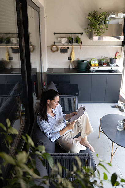istock Woman Reading Notebook on Terrace with Outdoor Kitchen and Greenery 2228819354