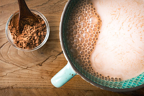 A close-up of a ceramic mug filled with creamy hot chocolate with milk, freshly whisked to create a smooth and frothy texture