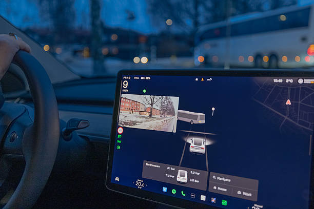 Sweden. Uppsala. January 15, 2025. Female driver in Tesla Model Y electric car using autopilot with side camera view on winter street. S