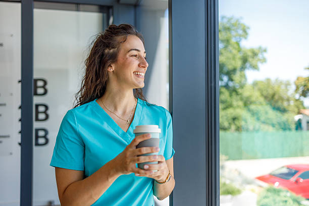 istock Smiling nurse taking a break with coffee by the window 2228830054
