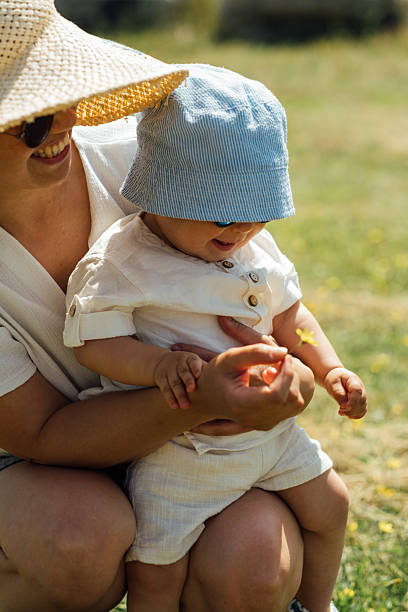 istock Mother holding baby while playing with a flower on a sunny day 2228832012